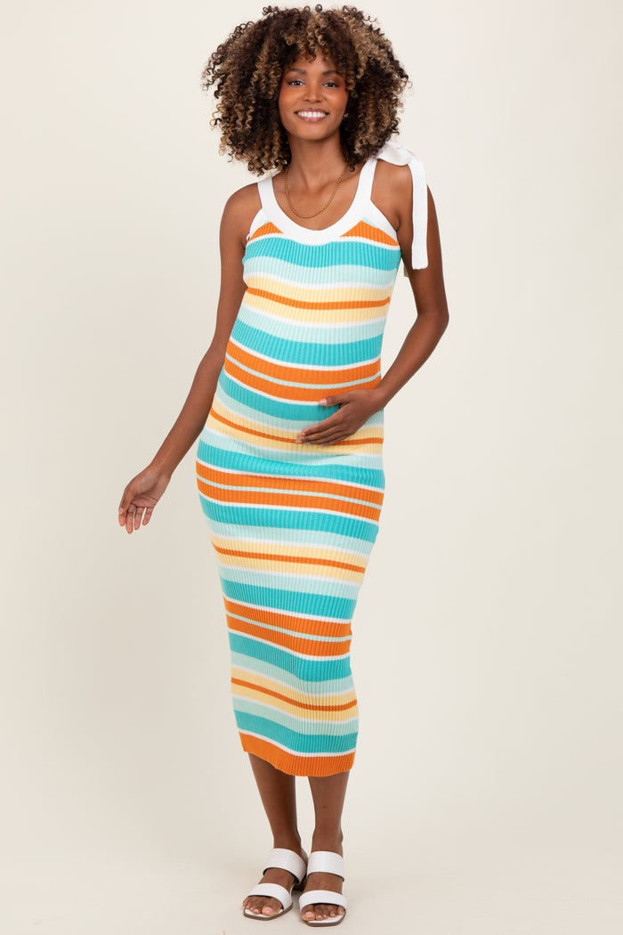 woman wearing a multicolored striped ribbed maternity dress with tied straps and holding her baby bump