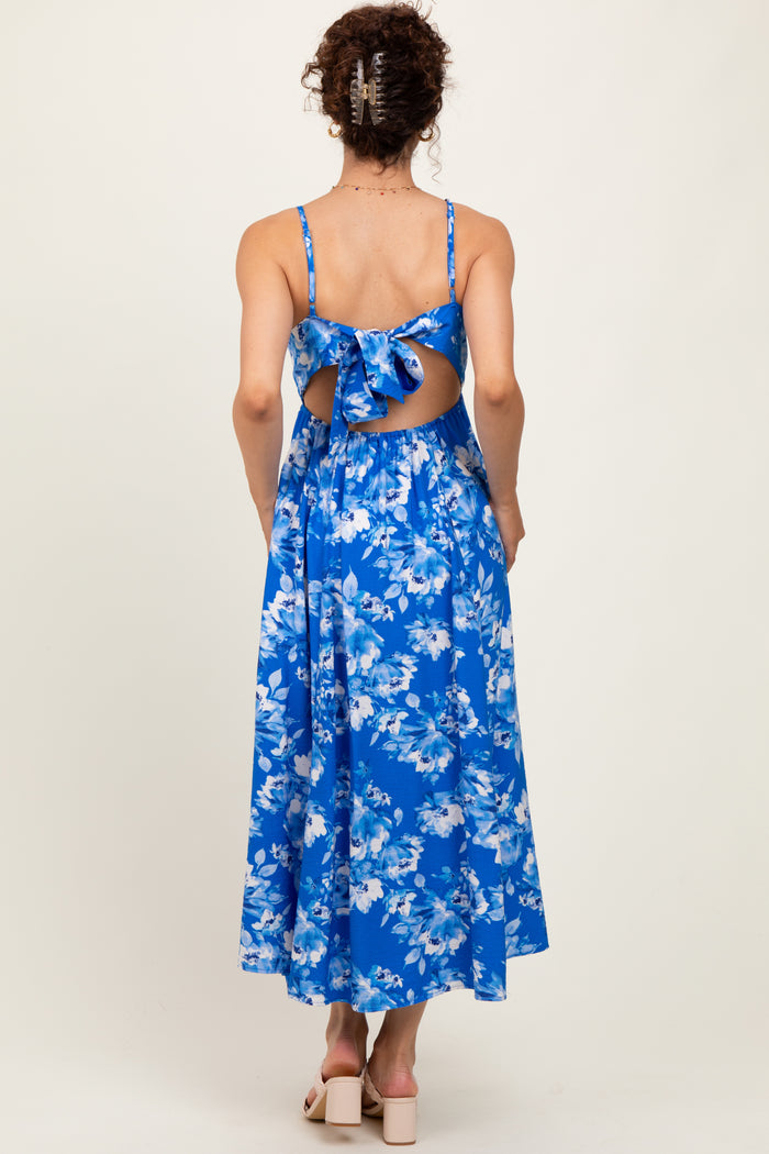 woman wearing a blue floral midi dress with a back tie detail and open back, showing a flowy skirt