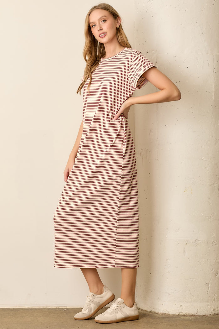woman wearing a light pink and white striped midi dress with short sleeves and side pockets
