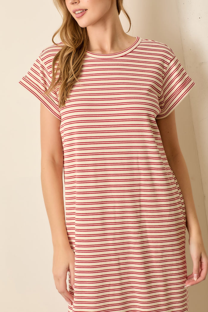 woman wearing a red and cream striped short sleeve t-shirt dress standing against a light background