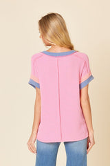 woman wearing a pink and blue striped short sleeve top, viewed from the back, with a relaxed fit and a ribbed texture