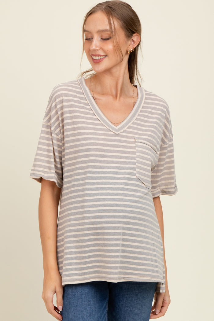 woman wearing a beige and gray striped maternity top with a pocket and v-neck, smiling, showcasing her baby bump