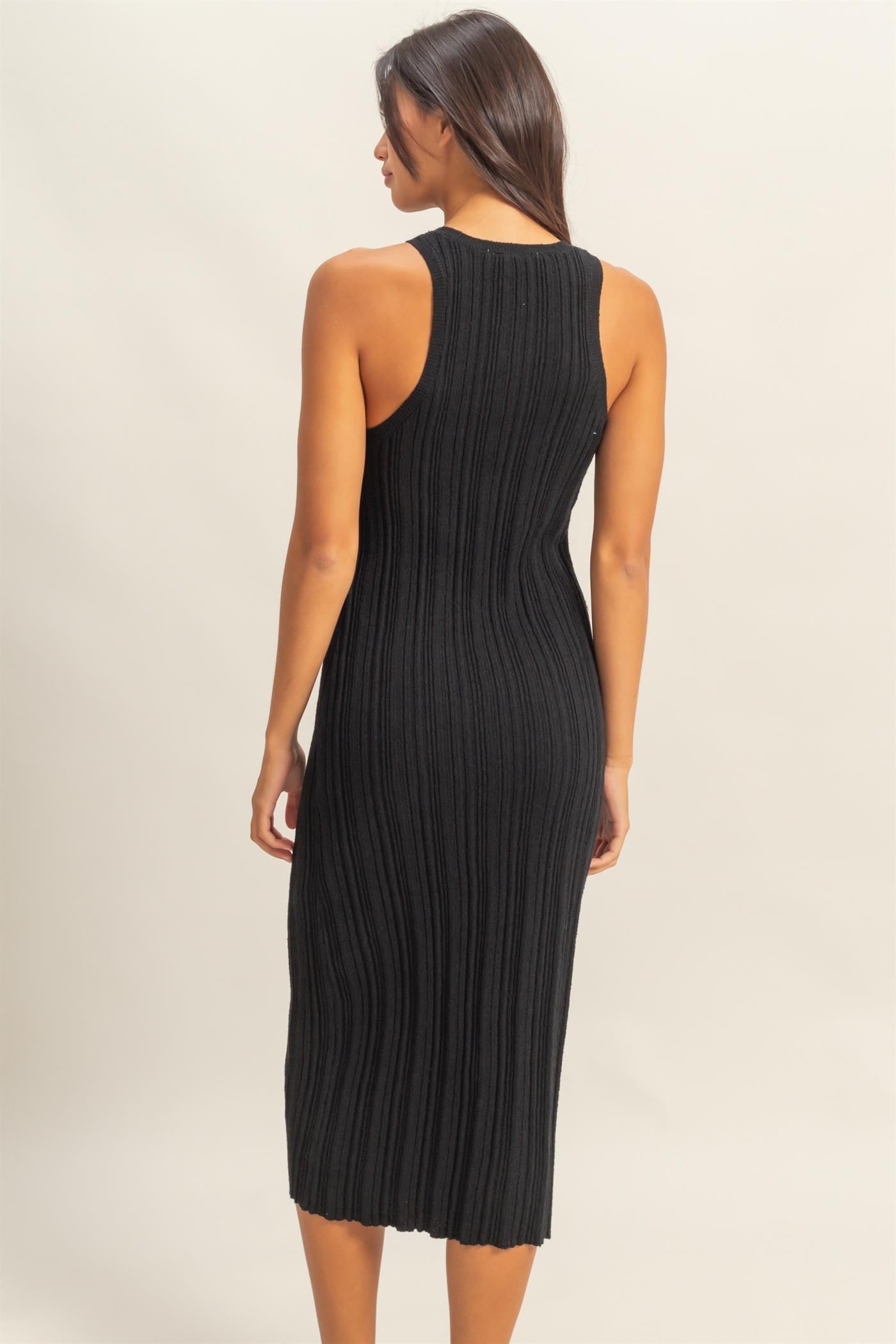 woman wearing a black ribbed midi dress with a sleeveless design and a fitted silhouette, viewed from the back