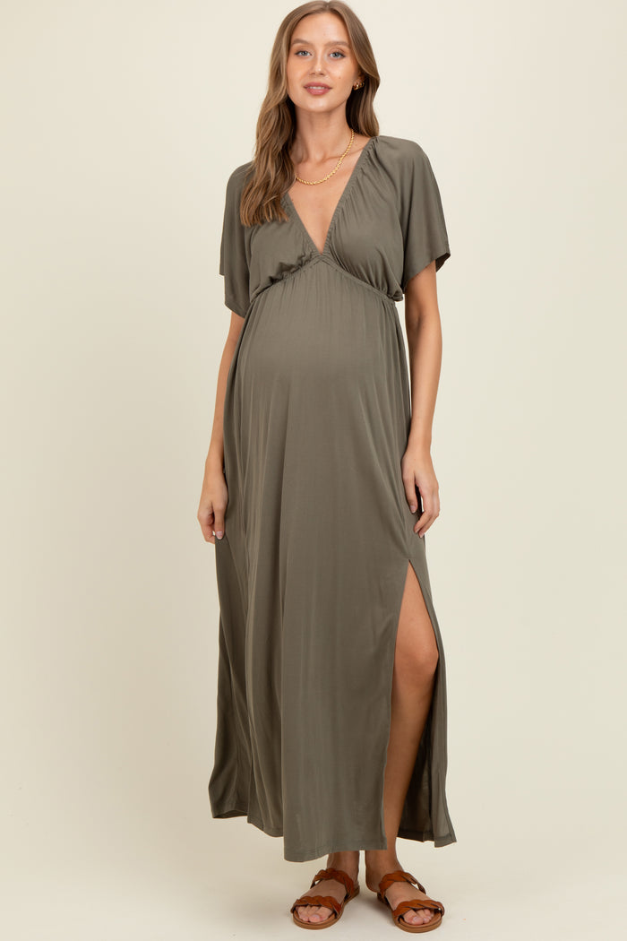 woman wearing a dark olive green maternity maxi dress with a wrap design and side slit, showing her baby bump