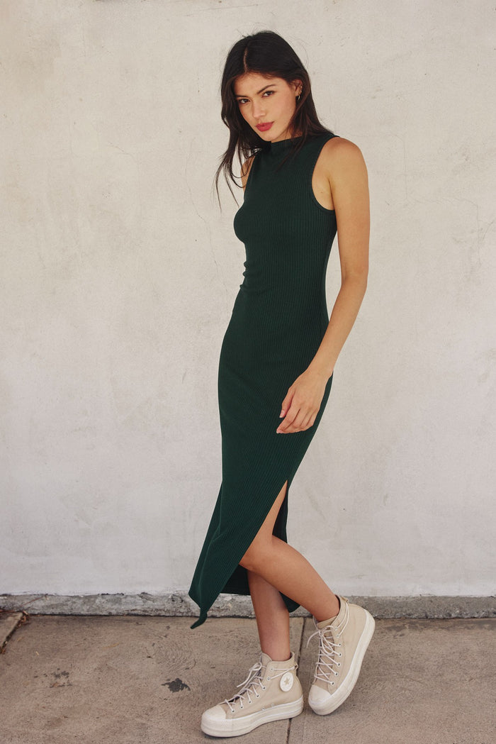 woman wearing a dark green ribbed midi dress with a side slit and beige platform sneakers