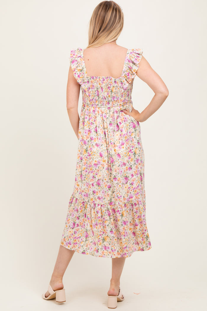 woman wearing a floral maternity dress with ruffled sleeves and a smocked back, displaying a baby bump