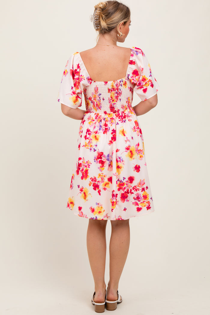 woman wearing a floral print short dress with puff sleeves and a smocked back detail