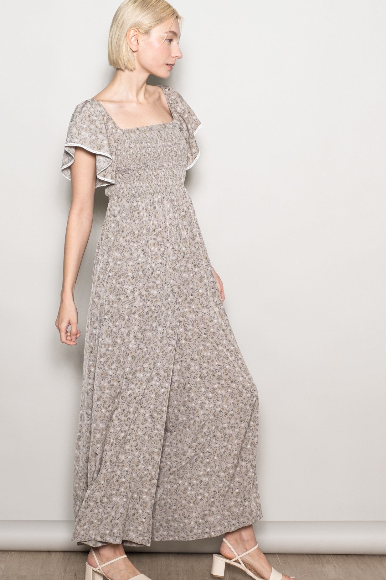 woman wearing a gray floral maxi dress with flutter sleeves and a square neckline