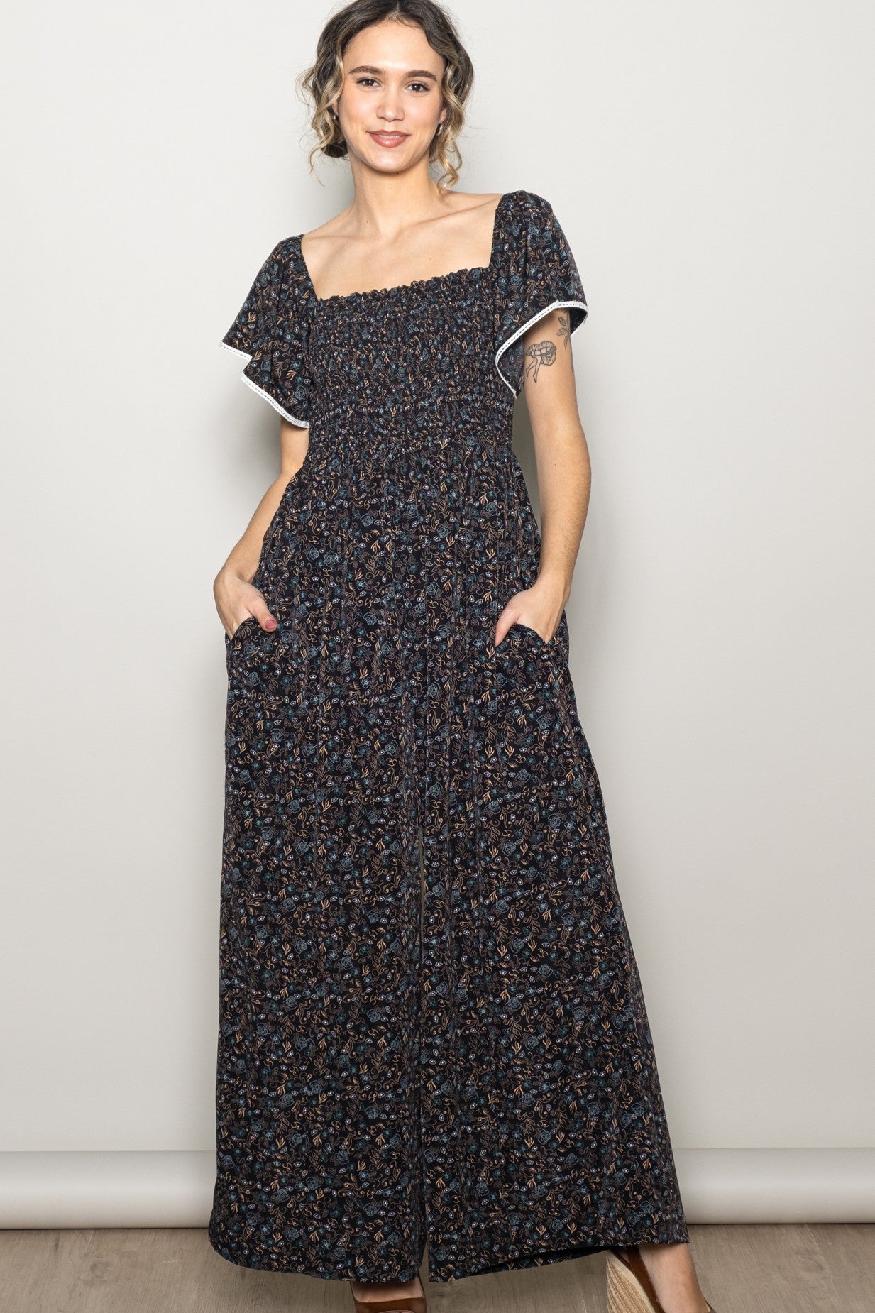 woman wearing a black floral print maxi dress with short puff sleeves and side pockets