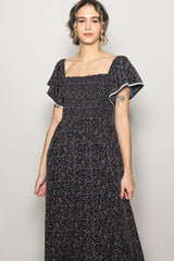 woman wearing a black floral maxi dress with smocked bodice and flutter sleeves