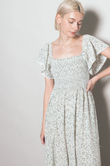 woman wearing a light floral smocked midi dress with flutter sleeves and a square neckline