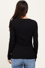 woman wearing a black long sleeve fitted top, seen from the back with her hair down and paired with blue jeans