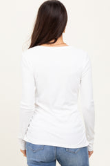 woman wearing a white long sleeve ribbed top with a fitted silhouette and round neckline, viewed from the back