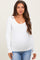 woman wearing a white long sleeve maternity top and showing her baby bump