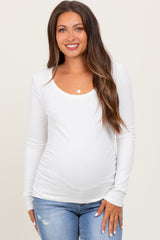 woman wearing a white long sleeve maternity top and showing off her baby bump