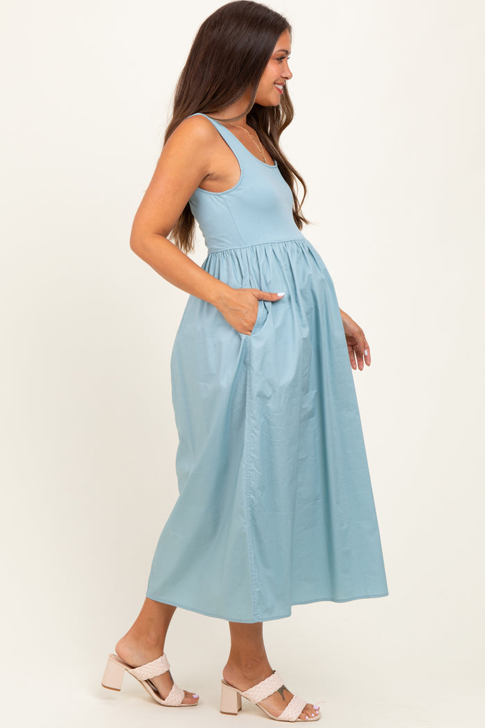 woman wearing a light blue maternity maxi dress with a fitted bodice and pockets, showcasing her baby bump