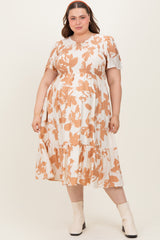 woman wearing a cream and rust floral print maternity dress with short sleeves and a tiered skirt, showcasing her baby bump