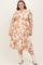 woman wearing a cream and rust floral print maternity dress with short sleeves and a tiered skirt, showcasing her baby bump