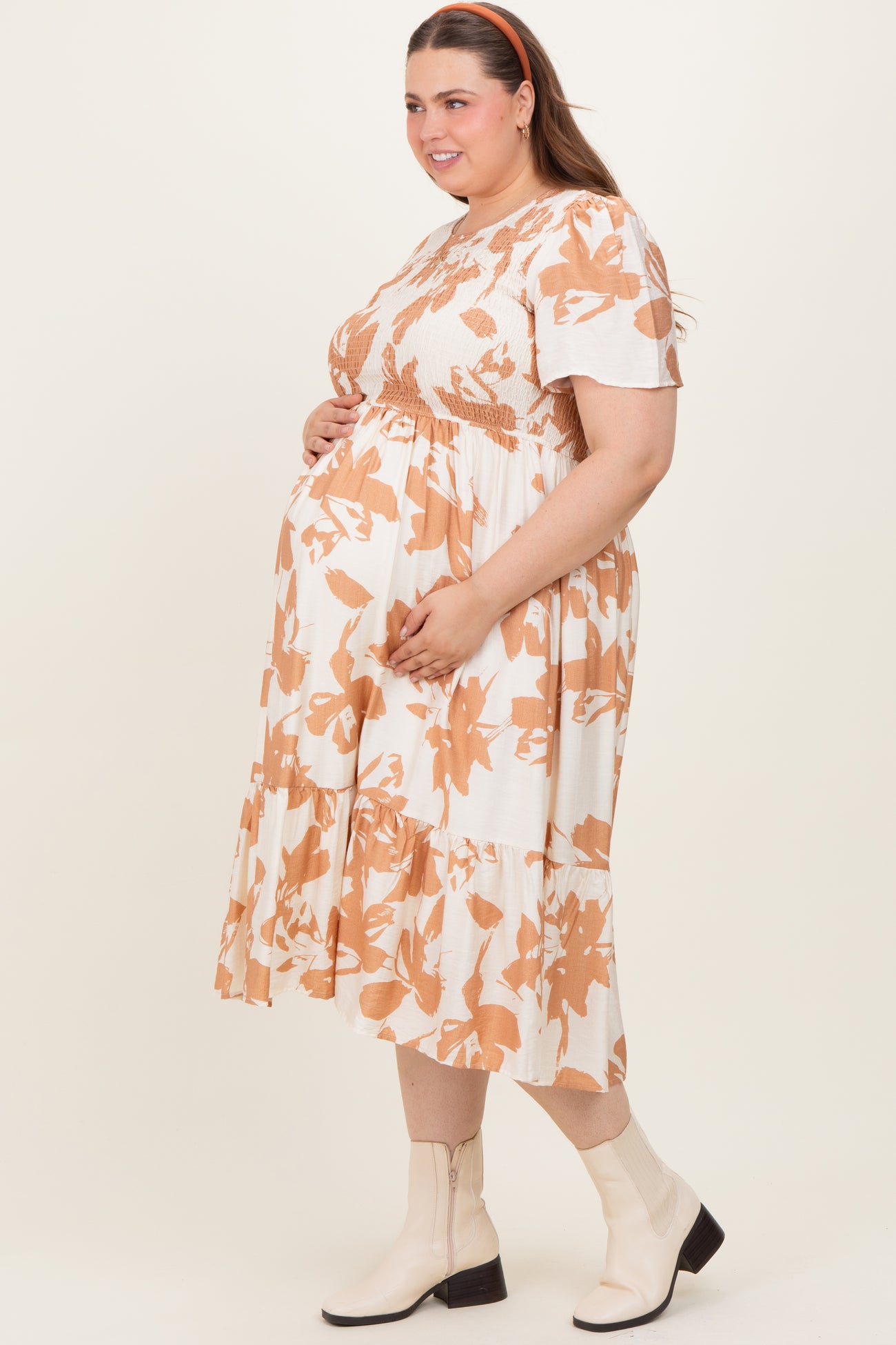 woman wearing a floral print maternity plus dress with short sleeves and a tiered skirt, showcasing her baby bump
