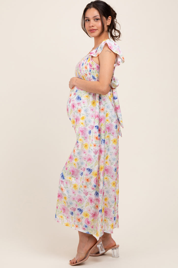 woman wearing a floral print maternity maxi dress with ruffle sleeves and holding her baby bump