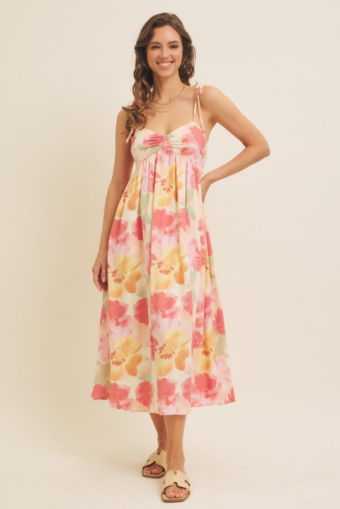 woman wearing a floral print midi dress with spaghetti straps and a gathered bodice, standing against a neutral background