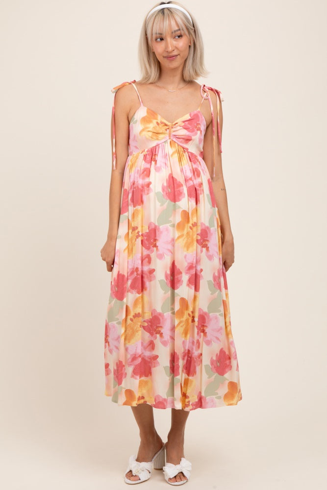 woman wearing a floral maternity dress with adjustable tie straps and a baby bump visible