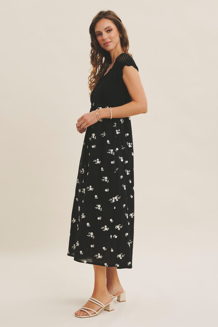 woman wearing a black floral maxi dress with short sleeves and a fitted bodice