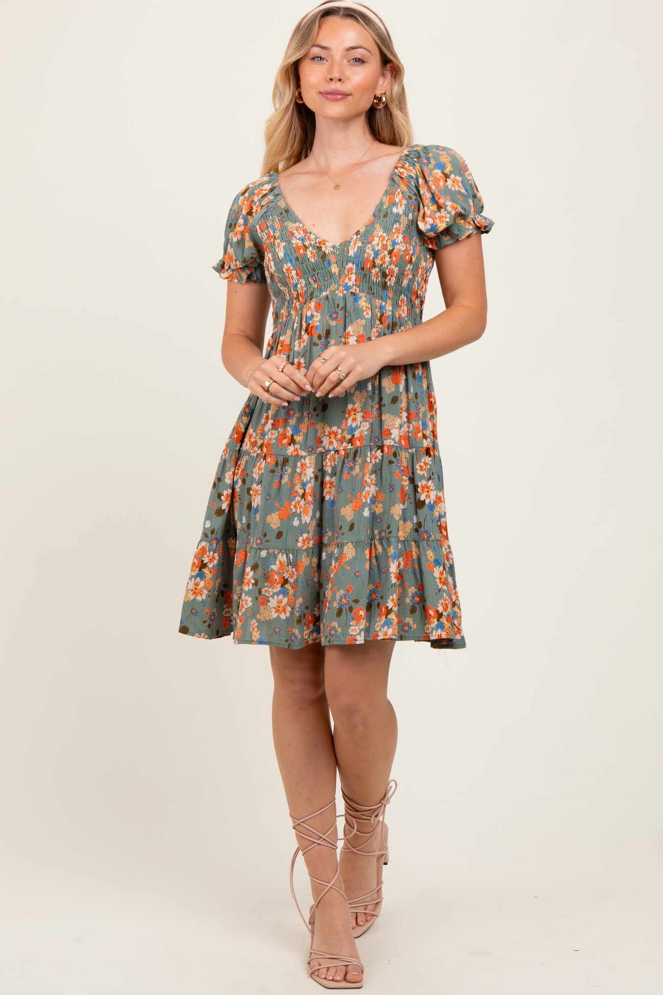 woman wearing a green floral puff sleeve dress with a smocked bodice and a tiered skirt