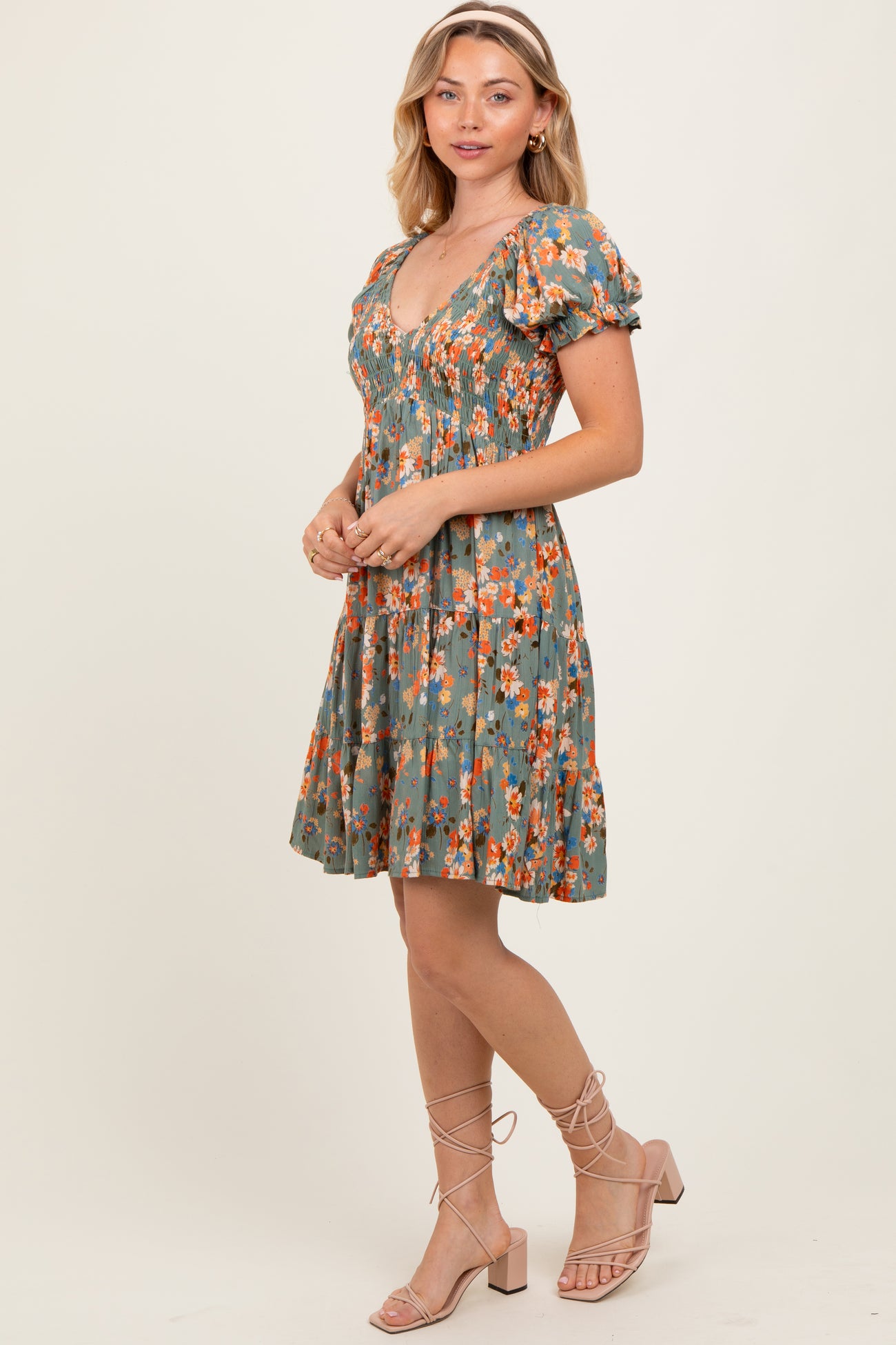 woman wearing a green floral puff sleeve dress with a fitted bodice and a flared skirt, standing sideways