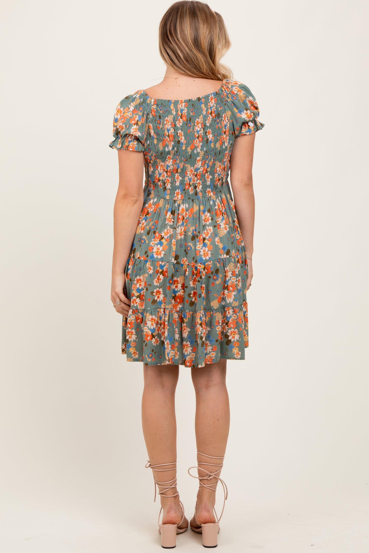 woman wearing a green floral print short sleeve dress with a smocked bodice and tiered skirt