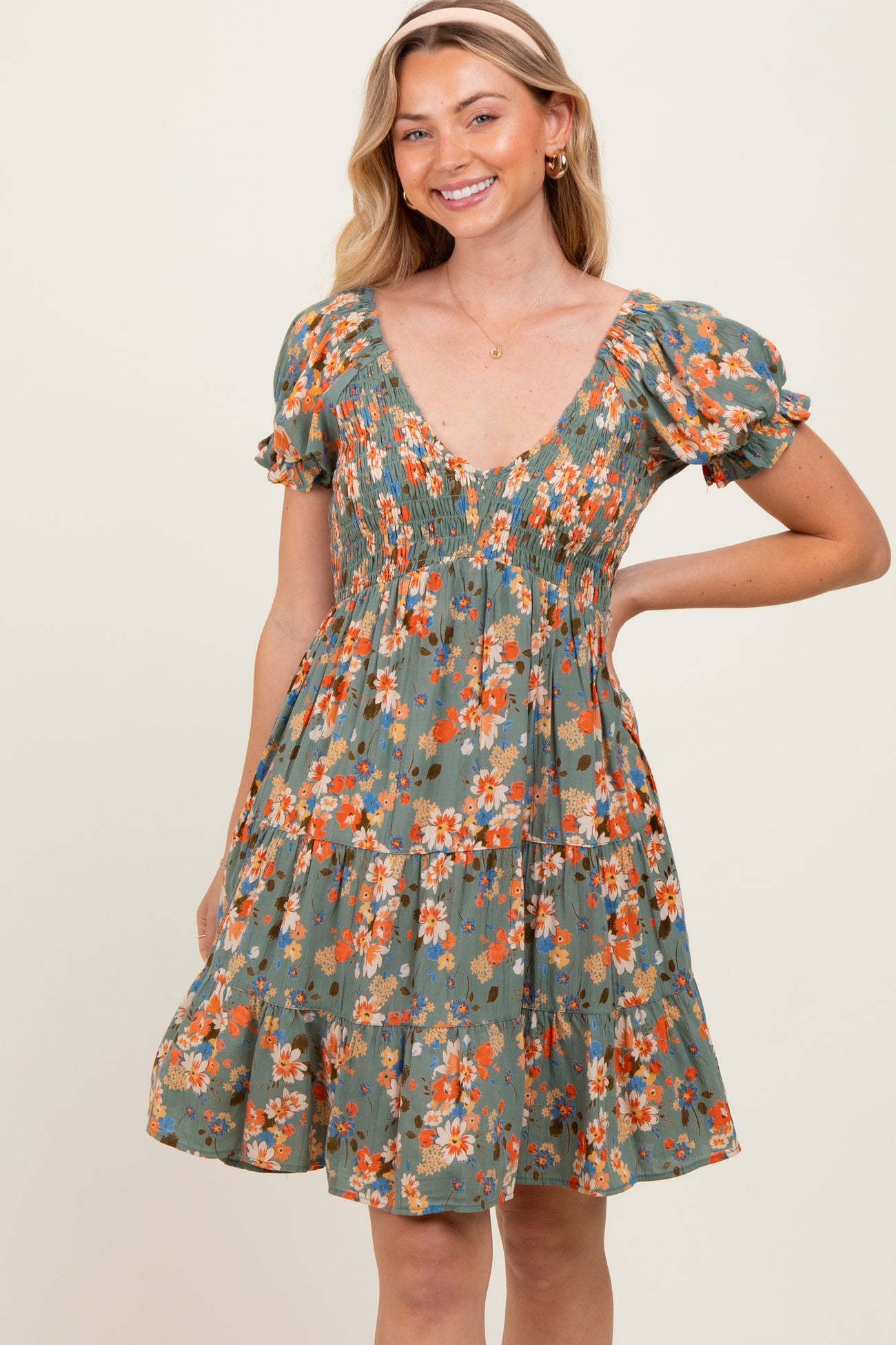 woman wearing a green floral print short dress with puff sleeves and a smocked bodice