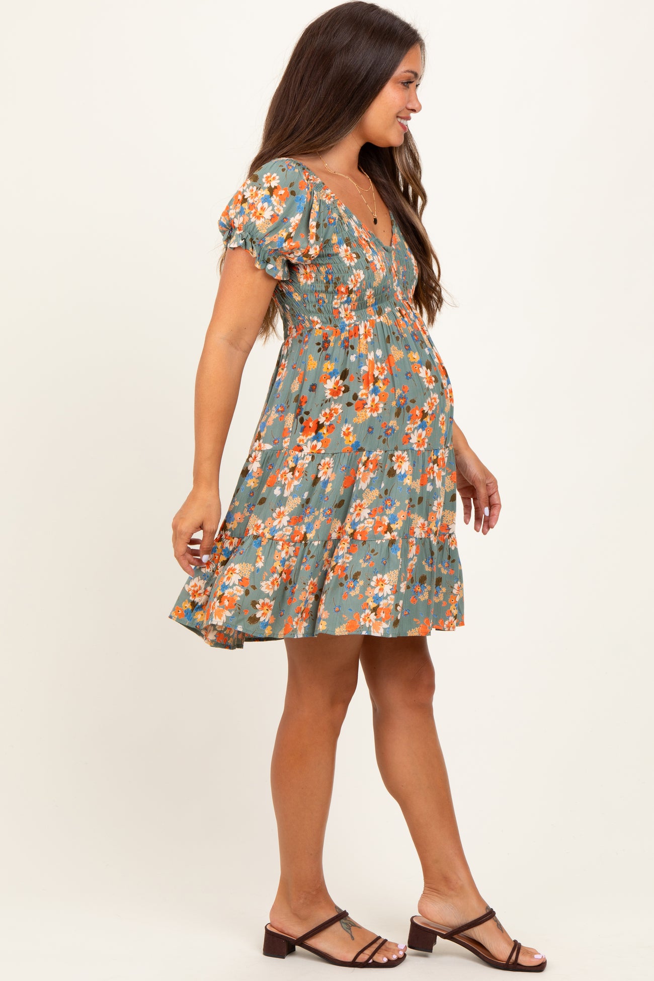 woman wearing a floral print green maternity dress with short puff sleeves and a baby bump visible