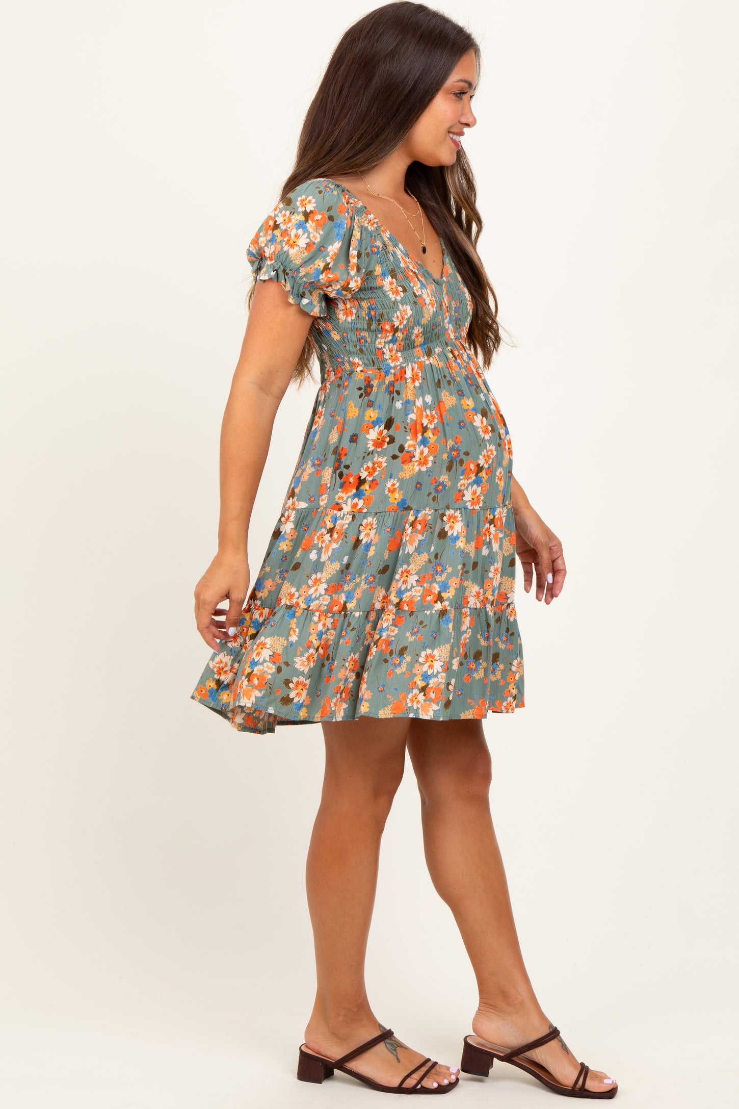 woman wearing a floral print green maternity dress with short puff sleeves and a baby bump visible