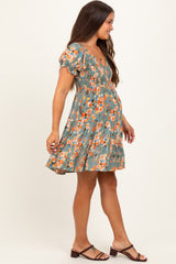 woman wearing a floral print green maternity dress with short puff sleeves and a baby bump visible