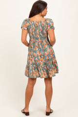woman wearing a green floral maternity dress with a smocked back and tiered skirt, viewed from the back