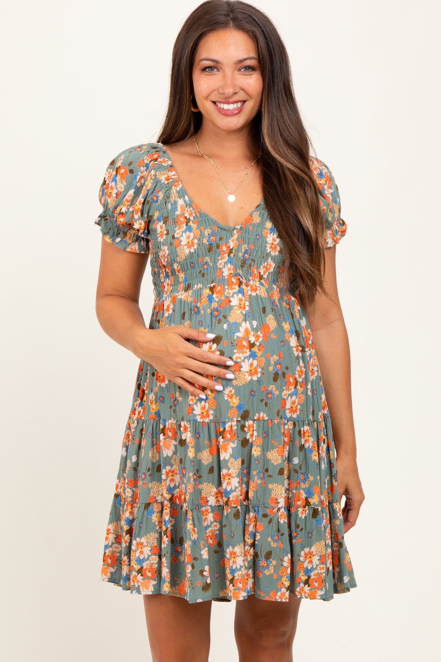 woman wearing a green floral maternity dress with puff sleeves and a baby bump visible
