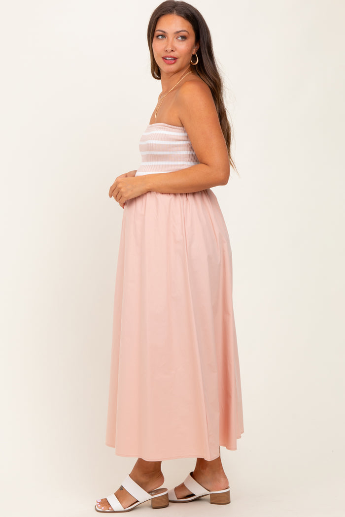 woman wearing a light pink maternity maxi dress with a smocked bodice and a flowing skirt, showing her baby bump