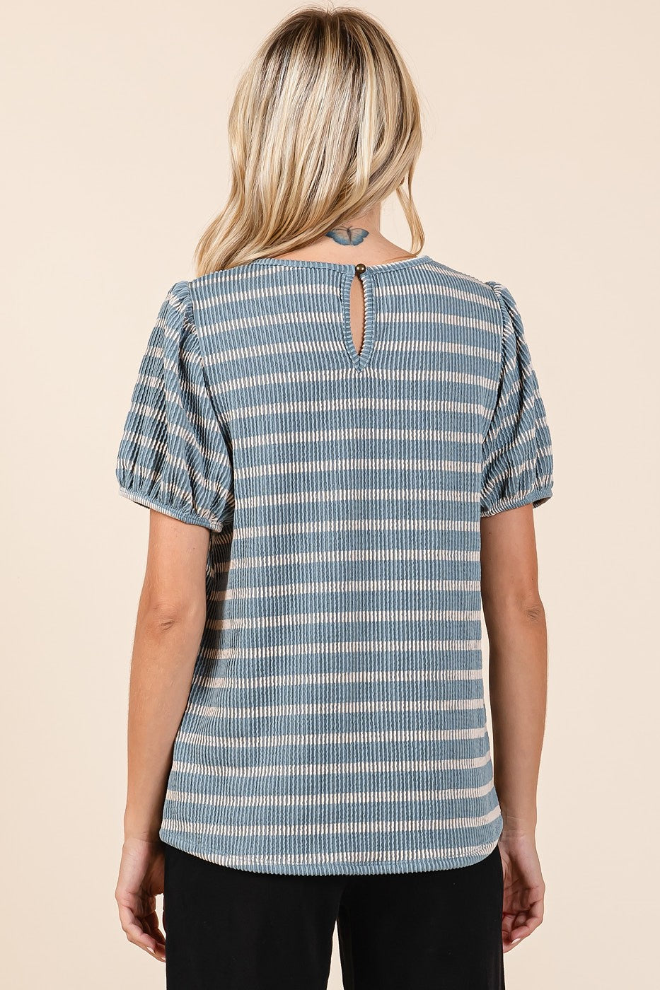 woman wearing a blue striped short sleeve top with a back keyhole detail and puffed sleeves