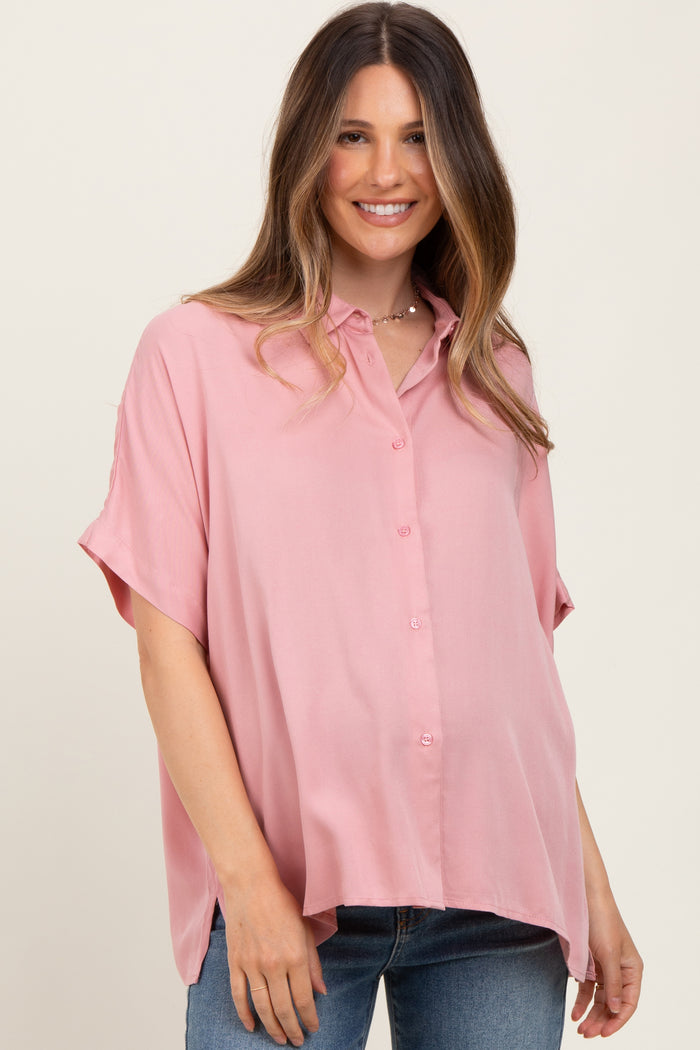 woman wearing a pink short sleeve button-up maternity shirt with a visible baby bump