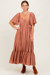 woman wearing a rust colored midi dress with puff sleeves and a tiered skirt, paired with orange ankle boots
