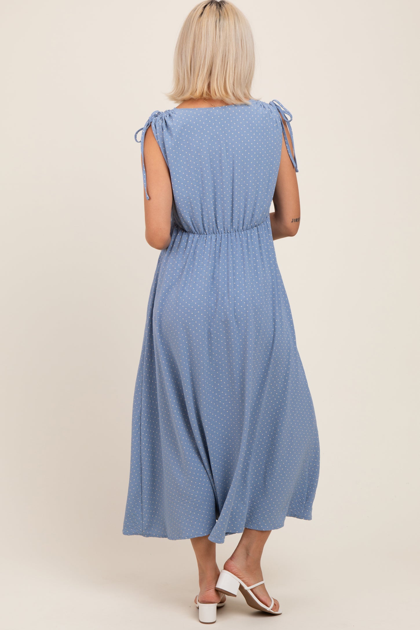 woman wearing a light blue maternity maxi dress with tie-up sleeves and a relaxed fit, showing a baby bump