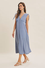woman wearing a light blue midi dress with tie straps and button details