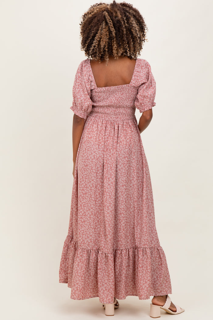 woman wearing a pink floral maternity maxi dress with puff sleeves and a tiered hem, showcasing a baby bump from the back