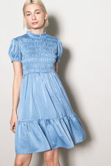 woman wearing a light blue smocked short sleeve dress with a tiered skirt