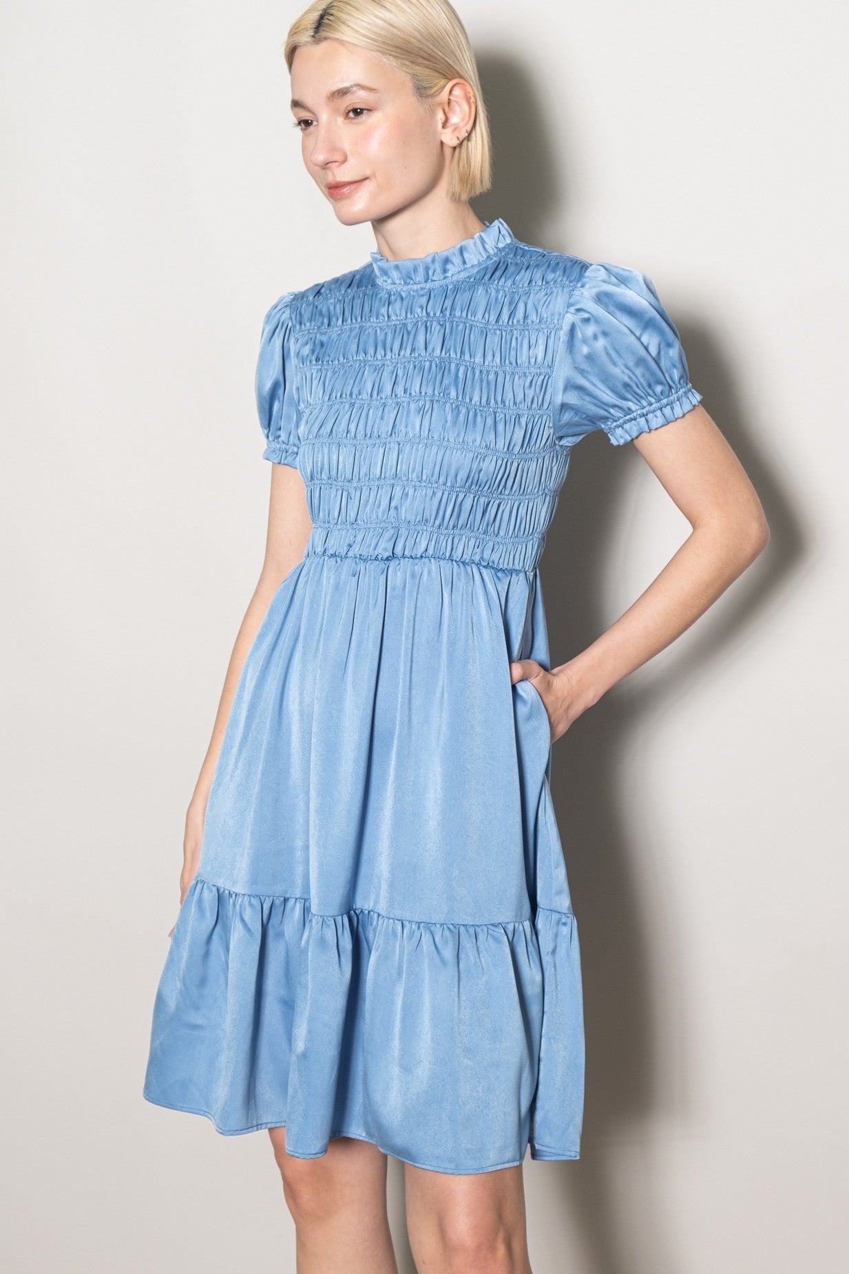 woman wearing a light blue smocked mini dress with puff sleeves and a tiered skirt