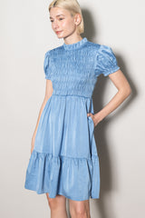 woman wearing a light blue smocked mini dress with puff sleeves and a tiered skirt
