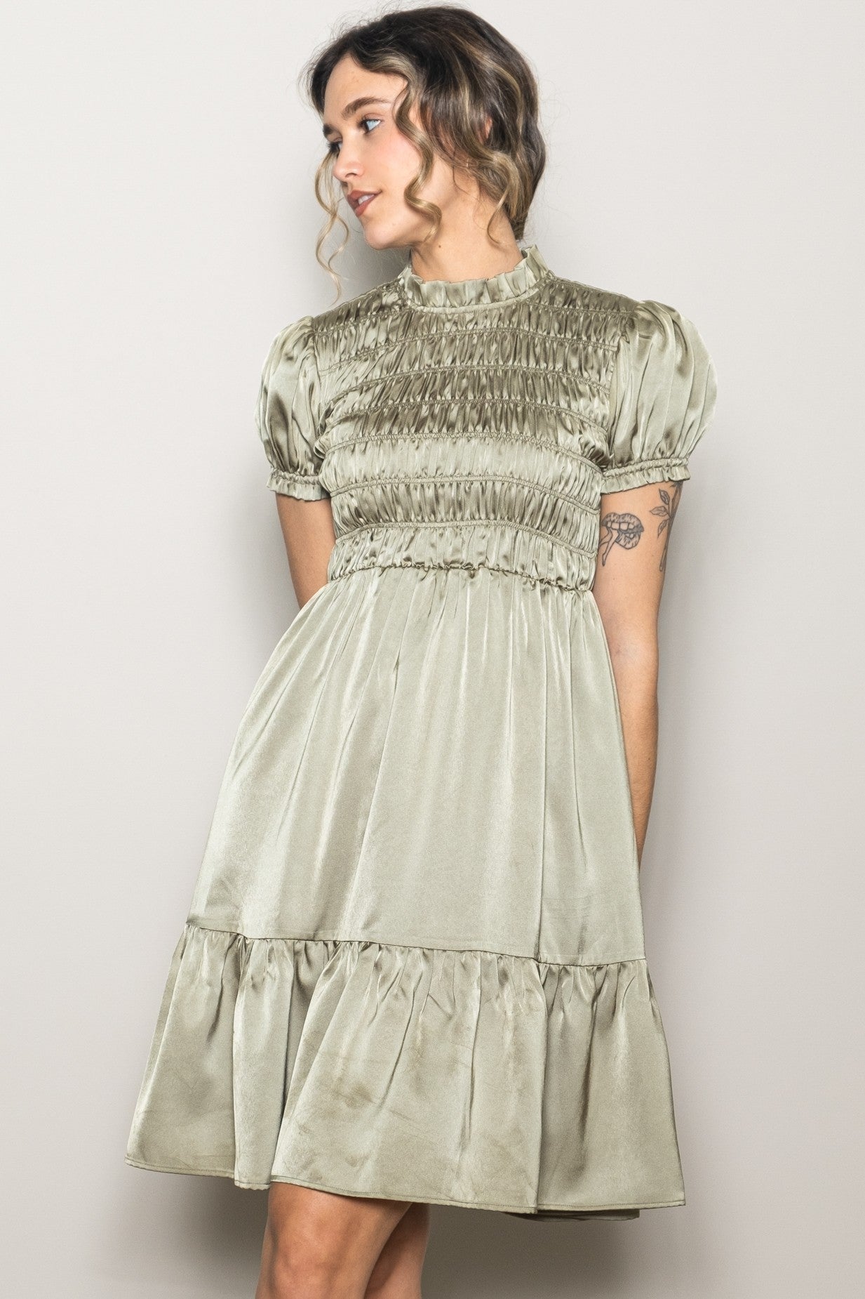 woman wearing a light green puff sleeve dress with smocking detail and a tiered skirt