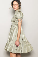 woman wearing a light green puff sleeve dress with a smocked bodice and a flared tiered skirt