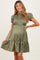 woman wearing an olive green smocked maternity dress with puff sleeves and a tiered ruffled hem, showcasing her baby bump