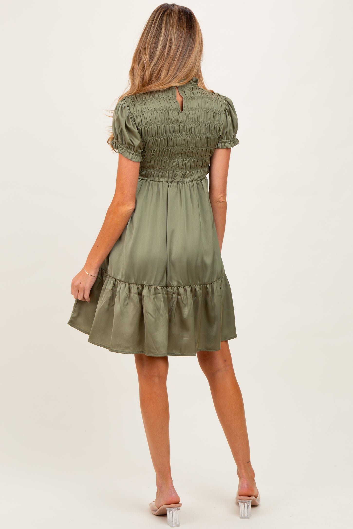 woman wearing a moss green maternity dress with smocked bodice and tiered skirt, showing the back view